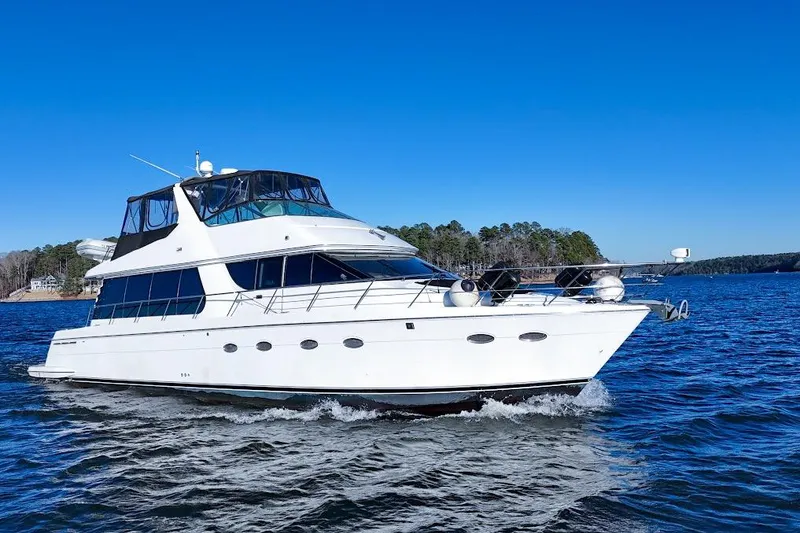 The Image of 2001 Carver 570 Voyager Pilothouse yacht cruising on a clear blue lake. - 0