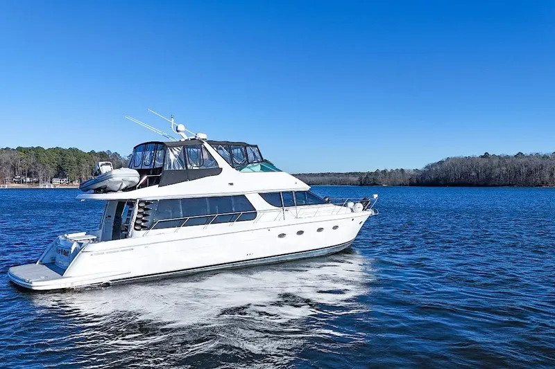 Slide: The Image of 2001 Carver 570 Voyager Pilothouse yacht cruising on a serene lake under clear blue skies. - 17