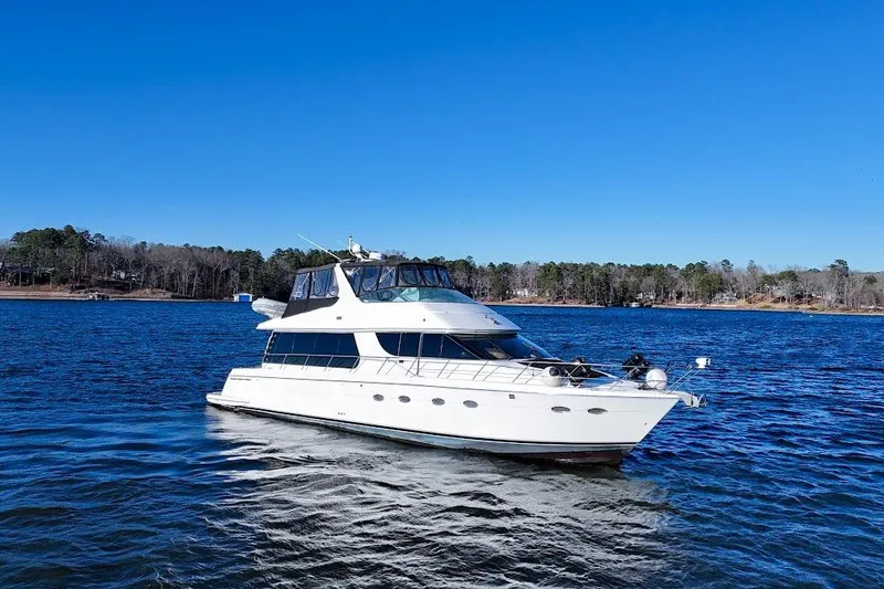 Slide: The Image of 2001 Carver 570 Voyager Pilothouse yacht on a serene lake under clear blue skies. - 3