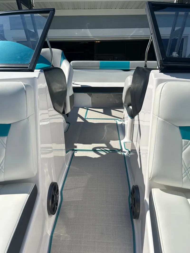 Slide: The Image of 2021 Regal 1900 ES Bowrider interior with white and teal seating, open cockpit view. - 12