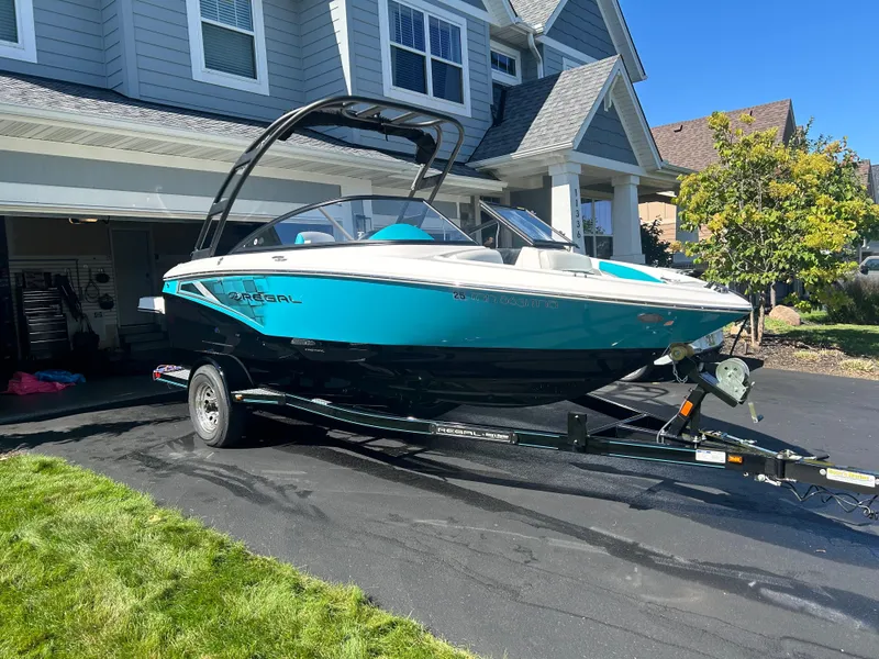 Slide: The Image of 2021 Regal 1900 ES Bowrider boat on trailer in driveway, sunny day. - 2