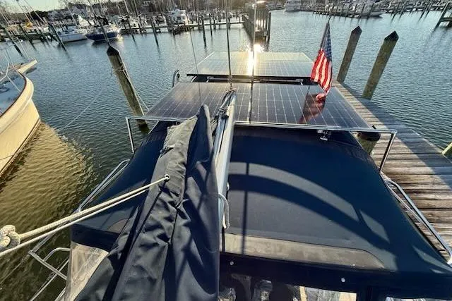 Slide: The Image of 1999 Caliber 40LRC sailboat with solar panels docked at a marina, featuring an American flag. - 24