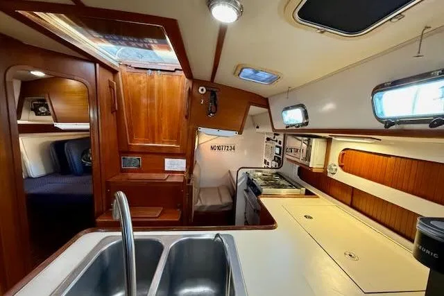 Slide: The Image of Interior of a 1999 Caliber 40LRC sailboat, featuring a kitchen and cozy cabin space. - 30