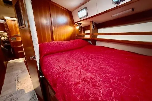 Slide: The Image of Cozy cabin interior of 1999 Caliber 40LRC yacht with red bedding and wooden paneling. - 42