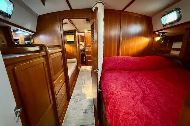 Slide: The Image of 1999 Caliber 40LRC yacht interior with wood paneling and red bedding. - 44