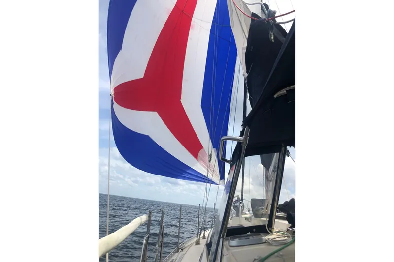 Slide: The Image of Sailing on a 1999 Caliber 40LRC with vibrant red, white, and blue spinnaker. - 55