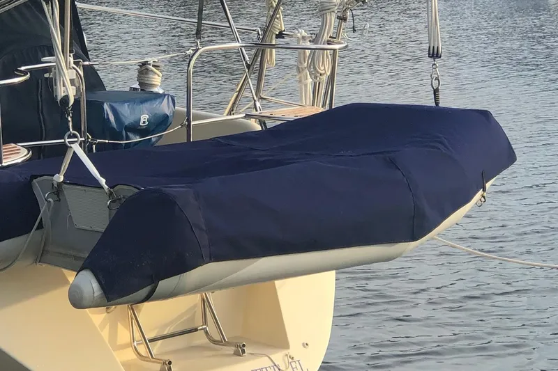 Slide: The Image of Covered dinghy on a 1999 Caliber 40LRC sailboat, docked on calm water. - 59