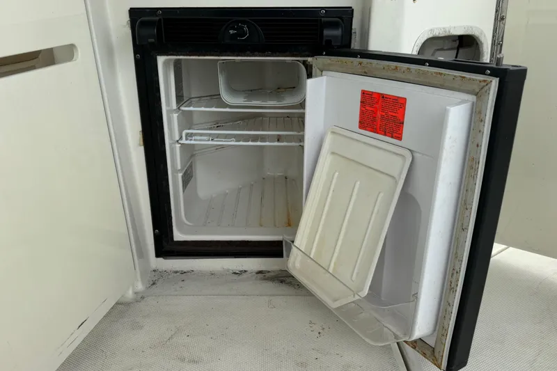 Slide: The Image of Open mini fridge on 2013 Sea Ray Sundancer 310 boat, showing interior shelves. - 12