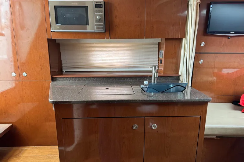 Slide: The Image of 2013 Sea Ray Sundancer 310 yacht kitchen with microwave, sink, and wooden cabinetry. - 32