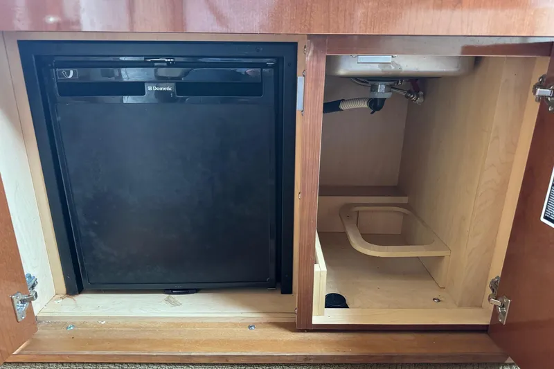 Slide: The Image of 2013 Sea Ray Sundancer 310 interior showing a Dometic fridge and storage space. - 34