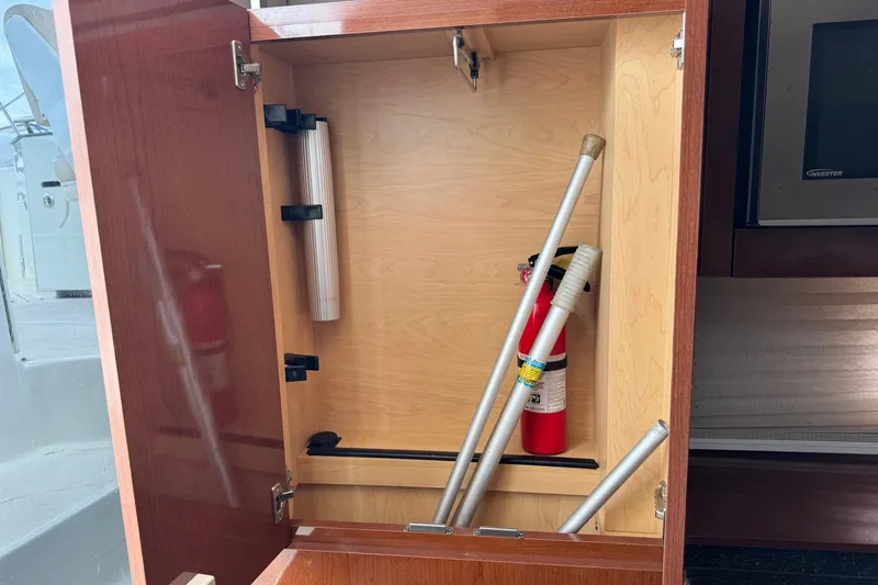 Slide: The Image of Open cabinet on 2013 Sea Ray Sundancer 310 with fire extinguisher and metal rods inside. - 36