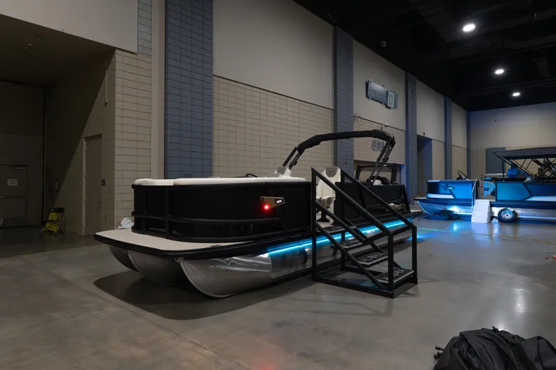 Slide: The Image of 2026 Alera M23Q pontoon boat displayed indoors with blue LED lighting. - 6