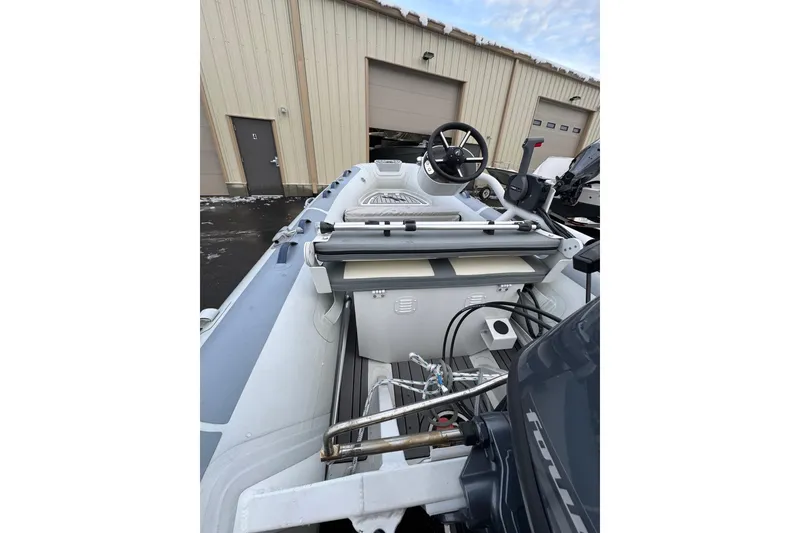 Slide: The Image of 2023 Highfield Classic 340 boat interior with steering wheel and engine, parked near a garage. - 14