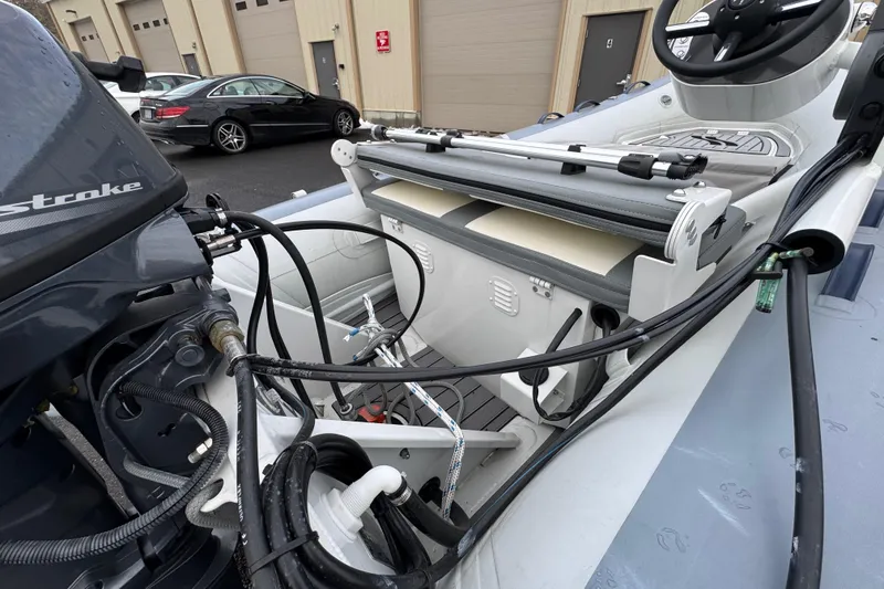 Slide: The Image of 2023 Highfield Classic 340 boat interior with motor and steering wheel, parked near buildings. - 5