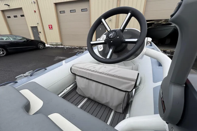 Slide: The Image of 2023 Highfield Classic 340 boat interior with steering wheel and seating, parked near a building. - 6