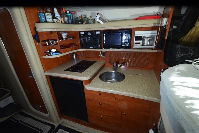 Slide: The Image of 2005 Rinker Fiesta Vee 342 boat kitchen with sink, stove, microwave, and storage shelves. - 28