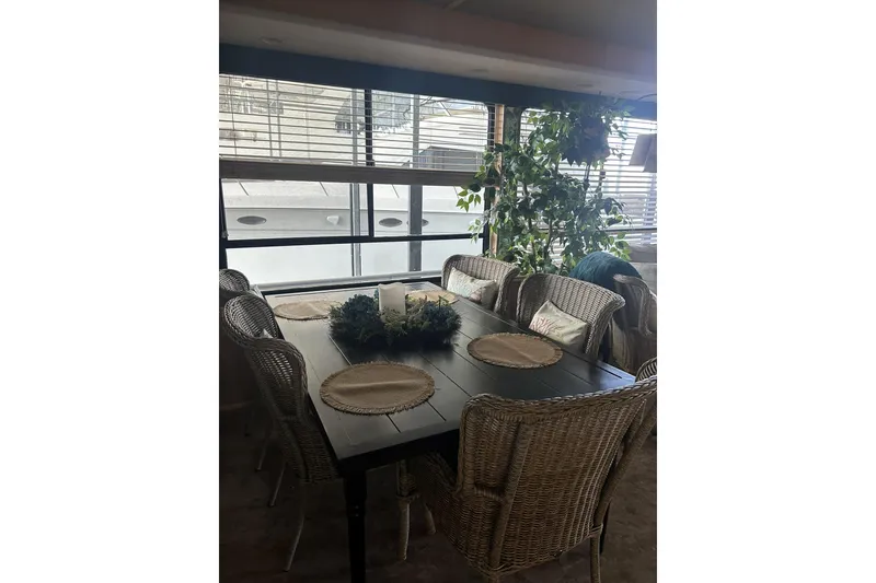 Slide: The Image of Dining area with wicker chairs and plants on a 1996 Sumerset 82'x18' Widebody houseboat. - 11