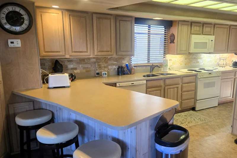 Slide: The Image of Kitchen interior of 1996 Sumerset 82'x18' Widebody houseboat with wooden cabinets and modern appliances. - 18