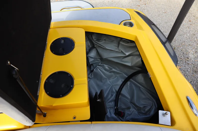 Slide: The Image of 2014 Centurion Enzo SS210 boat storage compartment with yellow interior and black hose. - 25