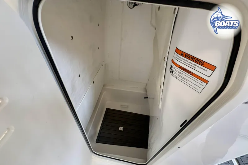 Slide: The Image of 2024 NauticStar 222 Offshore storage compartment with warning label and non-slip flooring. - 6