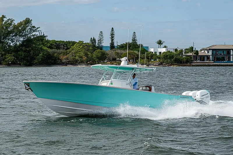 Slide: The Image of 2020 Valhalla Boatworks V-37 cruising on water, turquoise hull, scenic background. - 1