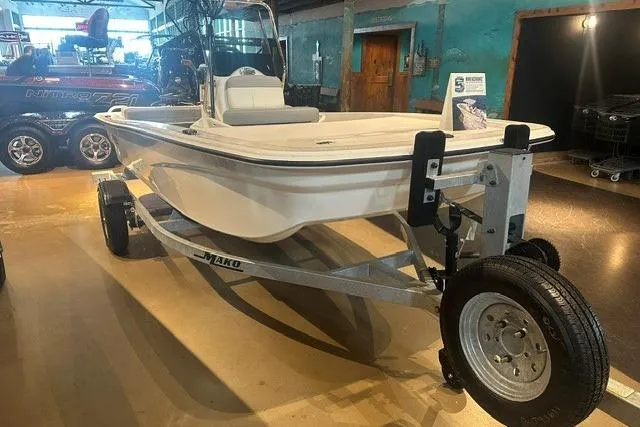 Slide: The Image of 2026 Mako Pro Skiff 13 CC boat on trailer in showroom setting. - 2