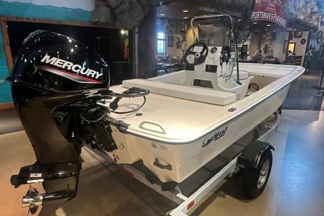 Slide: The Image of 2026 Mako Pro Skiff 13 CC boat with Mercury engine on display indoors. - 3