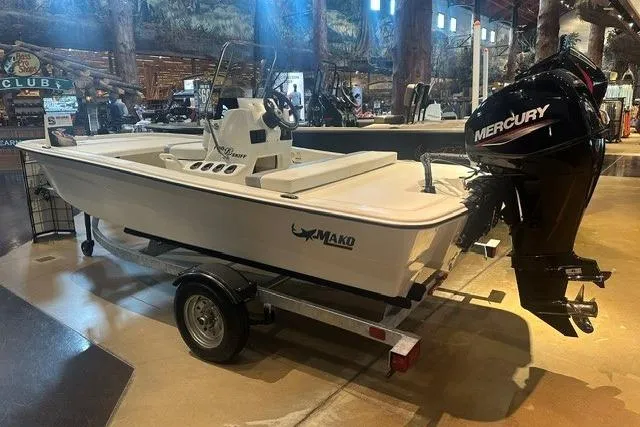 Slide: The Image of 2026 Mako Pro Skiff 13 CC boat with Mercury engine on display indoors. - 1