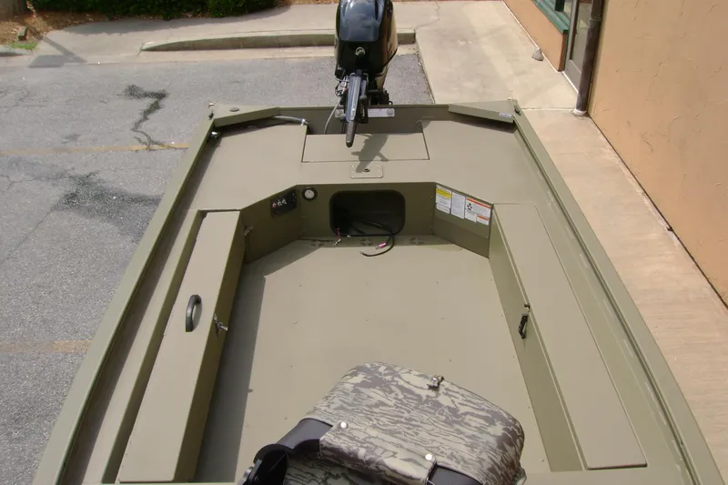 Slide: The Image of 2026 Tracker Grizzly 1654 T Sportsman boat interior with motor, parked outdoors. - 5