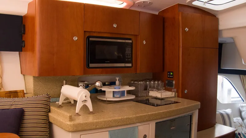 Slide: The Image of Intrepid 400 Cuddy 2017 kitchen with microwave and wooden cabinets. - 25