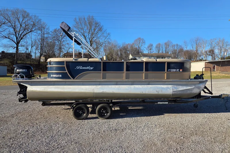 The Image of 2020 Bentley Pontoons 220 Navigator on trailer, parked outdoors, with Suzuki outboard motor. - 0