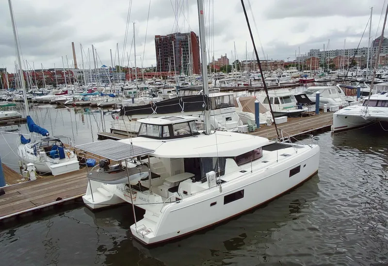 The Image of 2019 Lagoon 42 catamaran docked in a busy marina with other boats. - 0