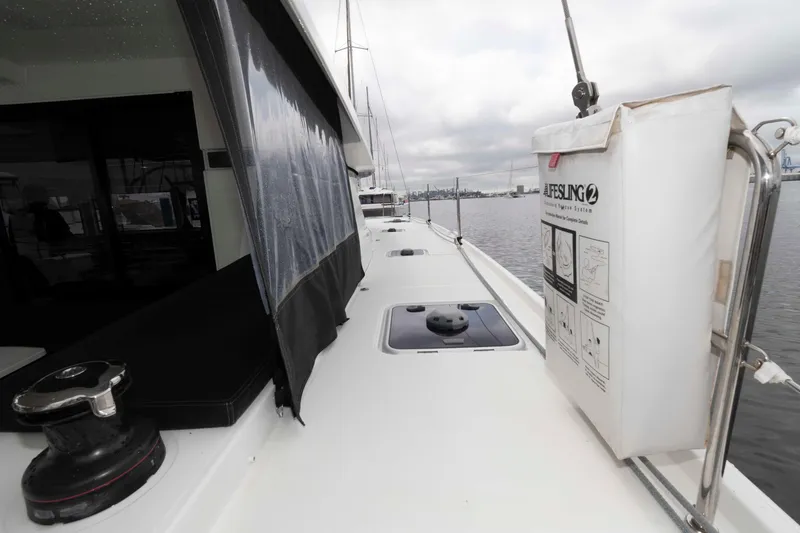 Slide: The Image of 2019 Lagoon 42 yacht deck with safety equipment and winch, docked by the water. - 20