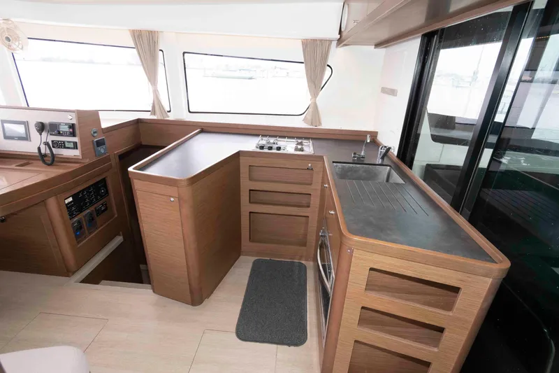 Slide: The Image of Interior of 2019 Lagoon 42 yacht featuring modern kitchen with wood cabinetry and appliances. - 26