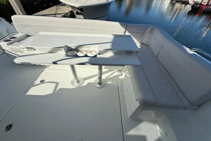 Slide: The Image of 2026 Beneteau Antares 12 boat deck with white seating and table, docked by water. - 10