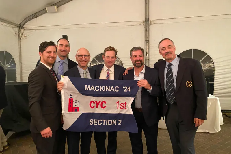 Slide: The Image of Group of men holding a "Mackinac '24 CYC 1st Section 2" flag at an event. - 10