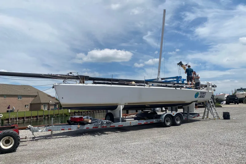 Slide: The Image of 2009 Farr 11s sailboat on trailer, people working, clear sky background. - 7