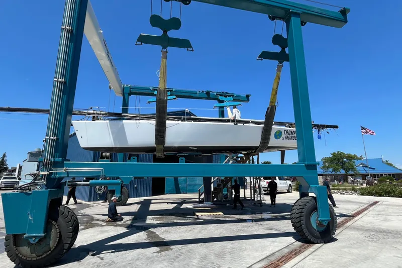 Slide: The Image of 2009 Farr 11s sailboat lifted by a large blue crane at a marina. - 8