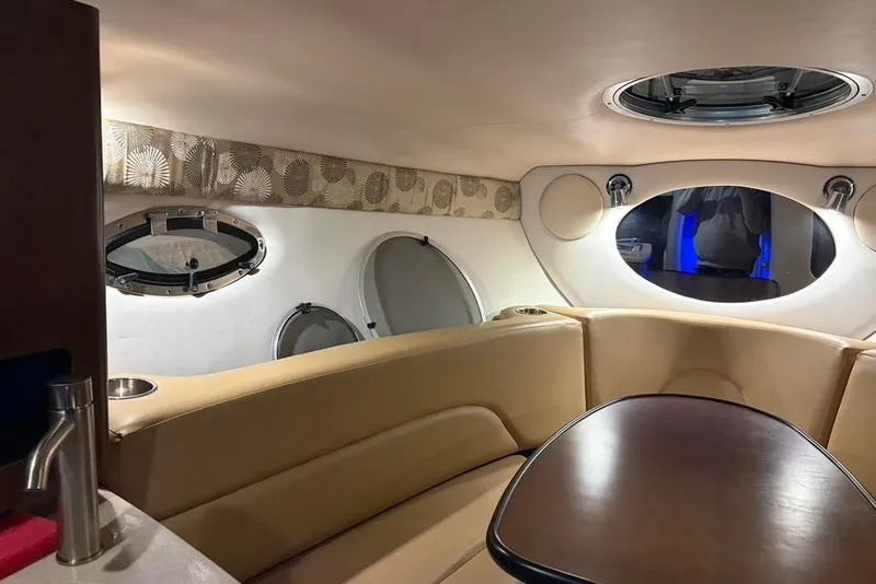 Slide: The Image of 2019 Crownline 264 CR cabin interior with beige seating and round table. - 14