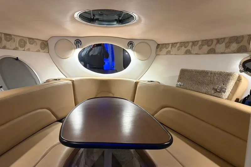 Slide: The Image of 2019 Crownline 264 CR cabin interior with beige seating and wooden table. - 16