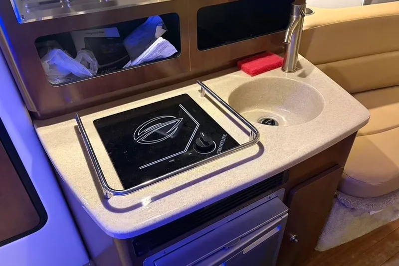 Slide: The Image of 2019 Crownline 264 CR boat kitchenette with stove, sink, and storage. - 21