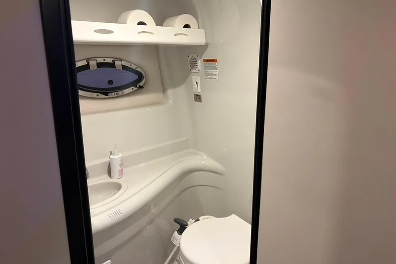 Slide: The Image of 2019 Crownline 264 CR boat bathroom with sink, toilet, and porthole window. - 25
