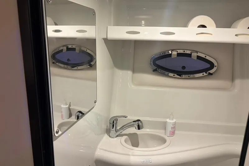 Slide: The Image of 2019 Crownline 264 CR boat bathroom with sink, mirror, and porthole window. - 26