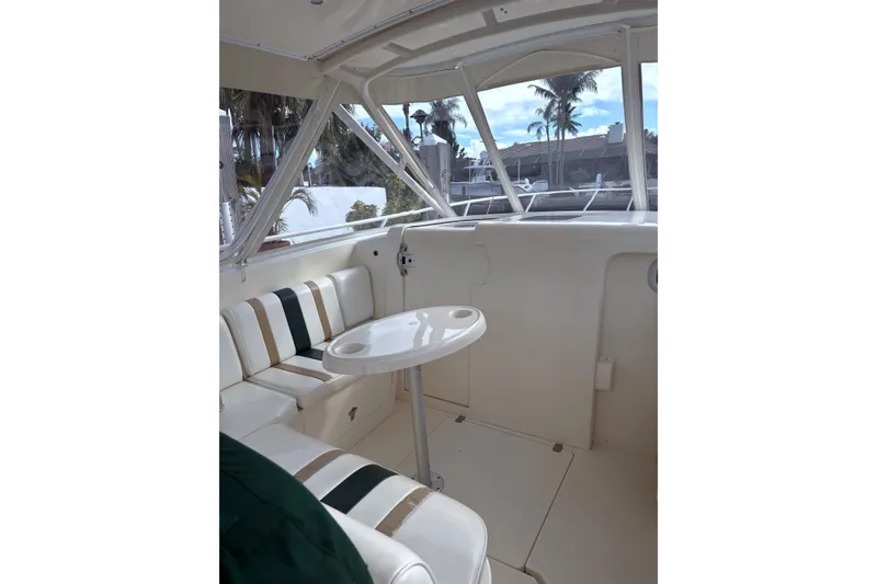 Slide: The Image of 2004 Intrepid 377 Walkaround interior with seating and table, featuring large windows and palm tree view. - 12