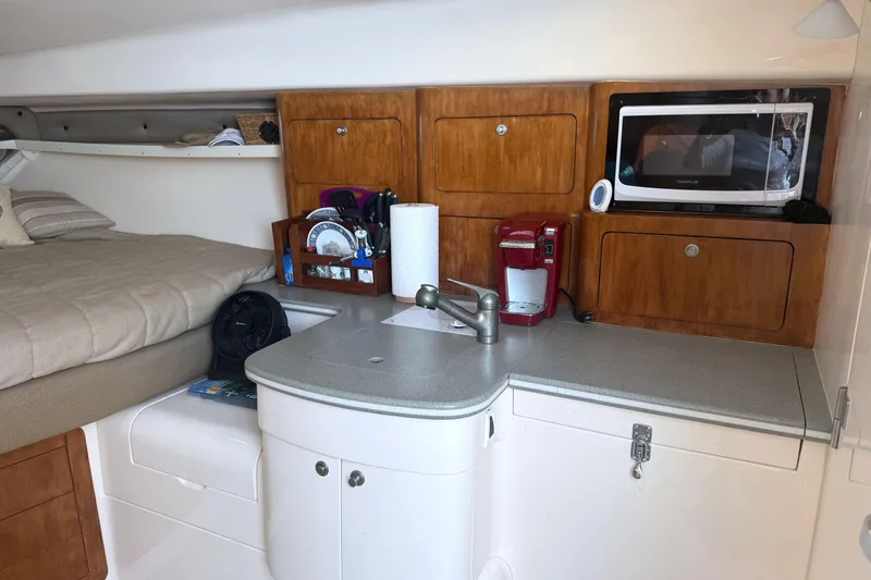Slide: The Image of 2004 Intrepid 377 Walkaround cabin interior with kitchenette, bed, and storage cabinets. - 17