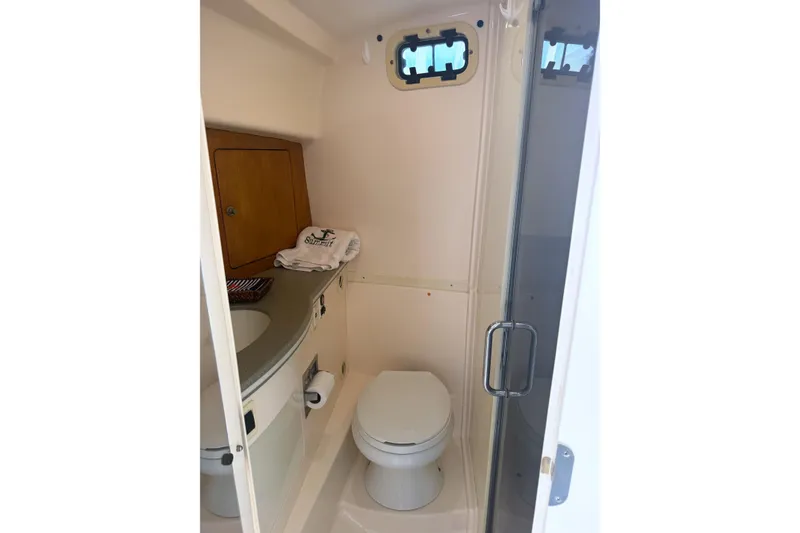 Slide: The Image of 2004 Intrepid 377 Walkaround boat bathroom with toilet, sink, and storage cabinet. - 19