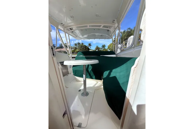Slide: The Image of 2004 Intrepid 377 Walkaround boat interior with green covers and table, tropical background. - 22