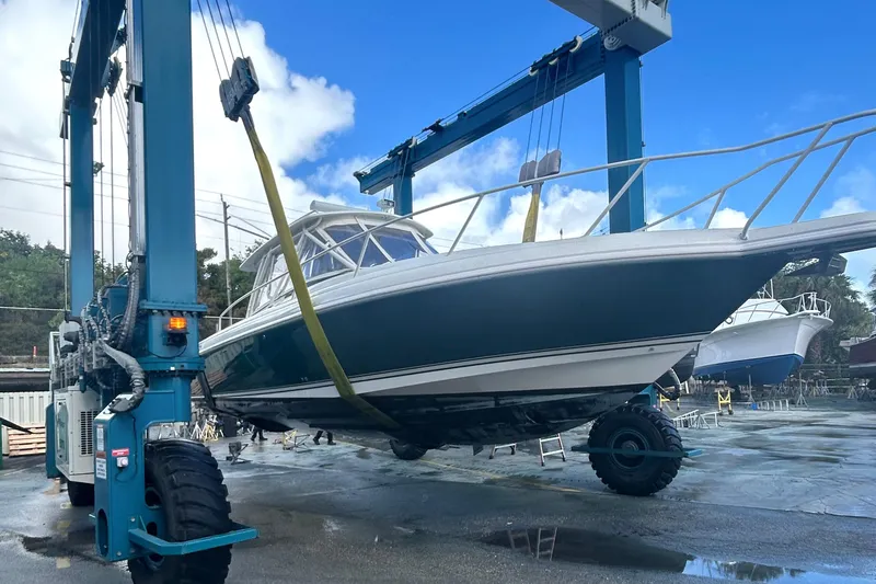 Slide: The Image of 2004 Intrepid 377 Walkaround boat being lifted by a large crane in a shipyard. - 26