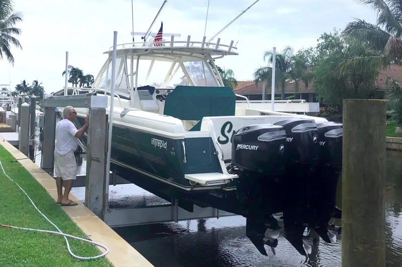 Slide: The Image of 2004 Intrepid 377 Walkaround boat with Mercury engines on a lift by the dock. - 28