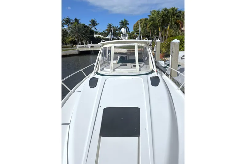 Slide: The Image of 2004 Intrepid 377 Walkaround boat docked near palm trees and clear skies. - 3
